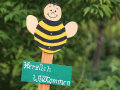 Eine Biene aus Holz auf der Herzlich Willkommen steht.