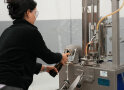 Eine Frau bearbeitet eine Flasche Cidre an einer Maschine