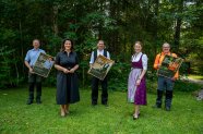 Mehrere Personen halten Plakate vor einem Waldrand