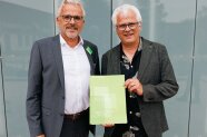 Der Präsident und Jörg Ewald vor einer Gebäudefassade. 