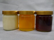 zu sehen sind drei Honiggläser, gefüllt mit einem sehr hellen HOonig, eins mit einem hellen flüssigen Honig und eins mit einem flüssigen dunklen Honig.