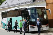 Kommission steigt aus einem Reisebus der vor einem Gebäude steht