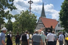 Leute laufen vorbei an Fachwerk, Kirche, Maibaum