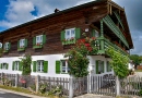 Traditionelles Haus mit Kletterrosen und Blumenkästen an den Fenstern.