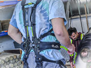 Ein Studierender trägt ein Exoskelett am Rücken.