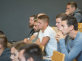 Studierende sitzend in der Aula mit Blick nach vorne zu den Rednern