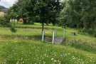 Holzbrücke über eine Graben in einer blühenden Wiese