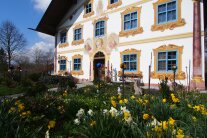 Osterglocken vor oberbayerischer Hausfassade mit Malerei