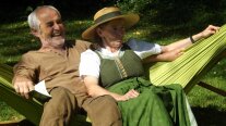 Ein Mann und eine Frau in ländlicher Kleidung in einer grünen Hängematte