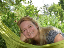 Portrait einer blonden Frau mit Sonnenbrille, liegt in einer Hängematte