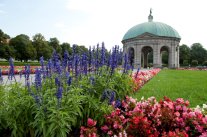 Blick über bunte Blumenrabatte auf einen Pavillon