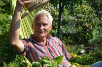 Mann in grüner Hängematte lupft seinen Strohhut