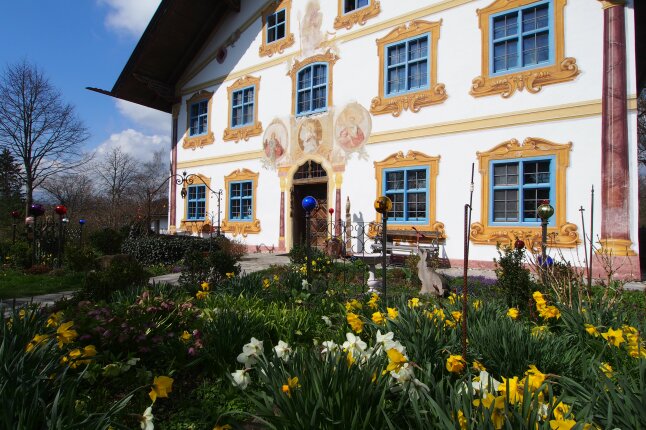 Osterglocken vor oberbayerischer Hausfassade mit Malerei