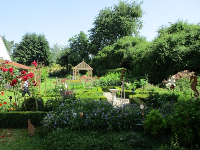 Blick über formalen Garten mit Buchshecken und Laube