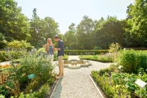 Besucher am kreuzförmig angelegten Kräutergarten mit Brunnen in der Mitte