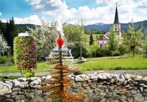 Blick über den Brunnen des Vereinsgartens auf die Kirche