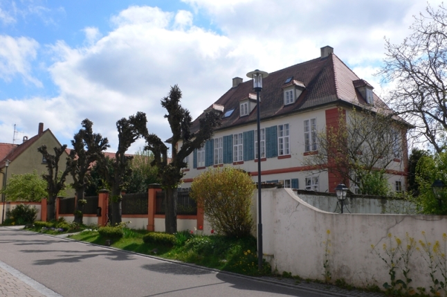 Blick von der Straße auf das historische Haus und den Vorgarten