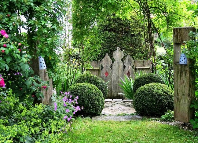 Blick in den Kuenstlergarten Nusser auf Holzdeko und Kugelbuchse