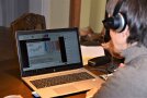 Frau mit Kopfhörer sitzt vor Laptop