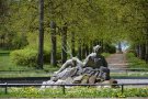 Blick auf Brunnen mit Neptun, im Hintergrund eine Allee