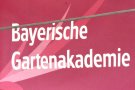 Bayerische Gartenakademie - Schriftzug in weiß auf dunkelrosa Grund