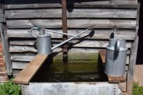 zwei Metallgießkannen an einem Wasserbecken