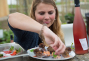 Eine Studierende verziert einen Teller voller Fingerfood mit Basilikum