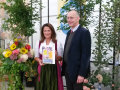 Michaela Kaniber hält die neue Broschüre neben Michael Kutter, Hintergrund Pflanzen und Blumen