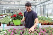 Ein Studierender im Gewächshaus mit einem Blumentopf in der Hand