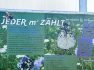 Ein beschrifteter Schild mit Vogel, Schmetterling, Biene und Blume abgebildet