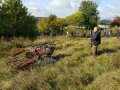 Links eine Mähraupe Köppl Crawler 23 im Einsatz beim Mähen; rechts steht der Bediener mit der umgehängten Fernsteuerung. Maschinenvorführung auf dem LWG-Gelände am 13.10.2021.