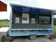 Autoanhänger mit Bildschirm und Plakaten als Ausstellungsbeitrag
