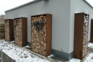 Modern gestaltete Holzlegen in Cortenstahleinfassung vor einer Gebäudewand als potenzieller Lebensraum für Insekten, Spinnen und Käfer. 