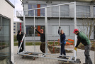 Mitarbeiter des Instituts für Stadtgrün und Landschaftsbau transportieren die fertiggestellten und verzinkten Rahmengestelle an die Fassadenprüfstände der Klima-Forschungs-Station.