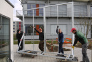 Mitarbeiter des Instituts für Stadtgrün und Landschaftsbau transportieren die fertiggestellten und verzinkten Rahmengestelle an die Fassadenprüfstände der Klima-Forschungs-Station.