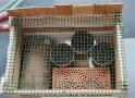 Eine Nisthilfe für Wildbienen mit Holz, Ziegel und Röhrchen
