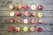 Viele unterschiedlich farbige Äpfel als Quadrat gelegt nebeneinander auf einem Holztisch