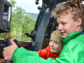 Zwei Kinder sitzen in der Kabine eines Traktors und lenken.