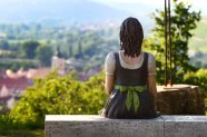 Blick auf die Rückseite einer sitzenden Weinprinzessinen Statue und auf den tiefer liegenden Ort und die dahinter liegende Landschaft