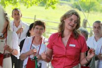 Gästeführerin mit Weinglas gestikuliert und spricht vor Zuhörern im Grünen.