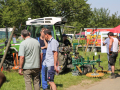 Winzer betrachten die ausgestellten Schlepper mit Anbaugeräten im Weinberg.